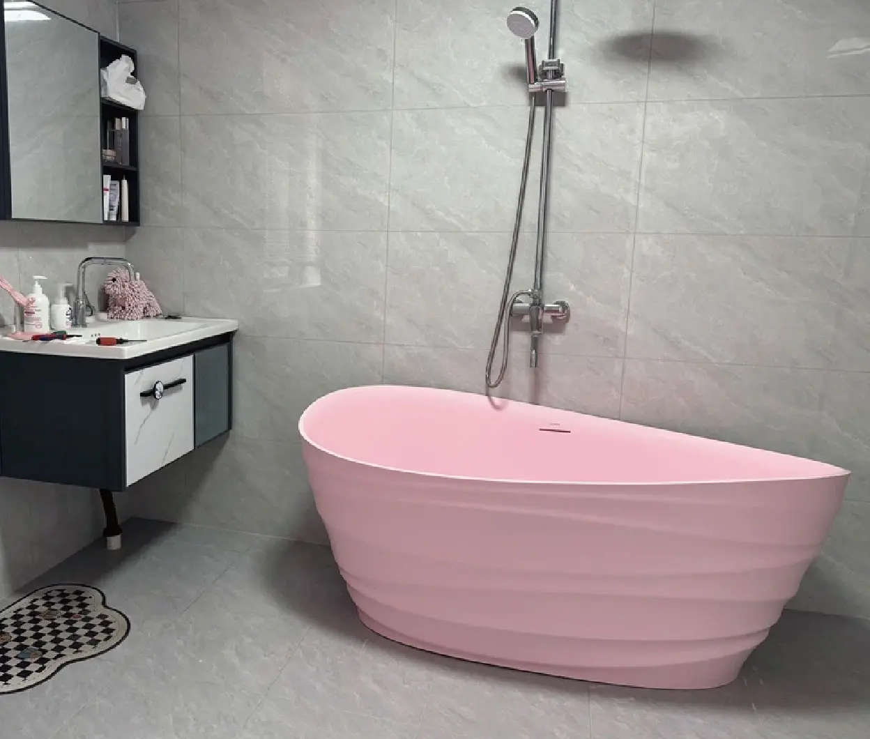 Pink bathtub in a gray tiled bathroom